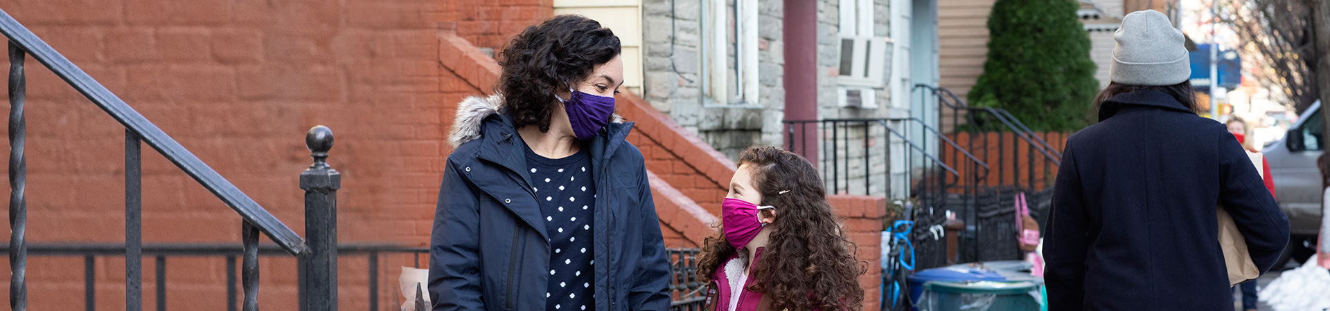  a mom and her daughter wearing winter clothes and face masks 